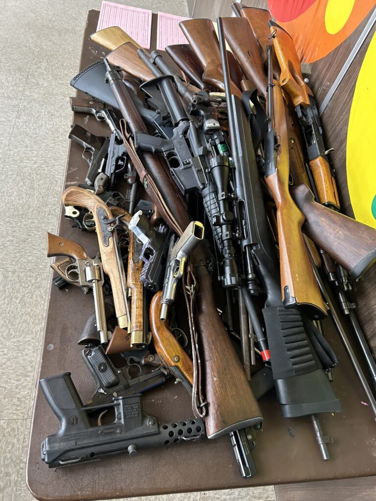 A pile of different types of guns on a table.